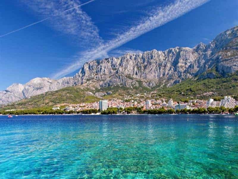 Blick vom Meer auf eine Stadt mit Bergkulisse in Dalmatien
