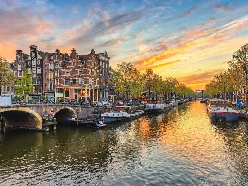 Grachte mit Schiffen, einer Brücke und traditionellen Häusern in Amsterdam